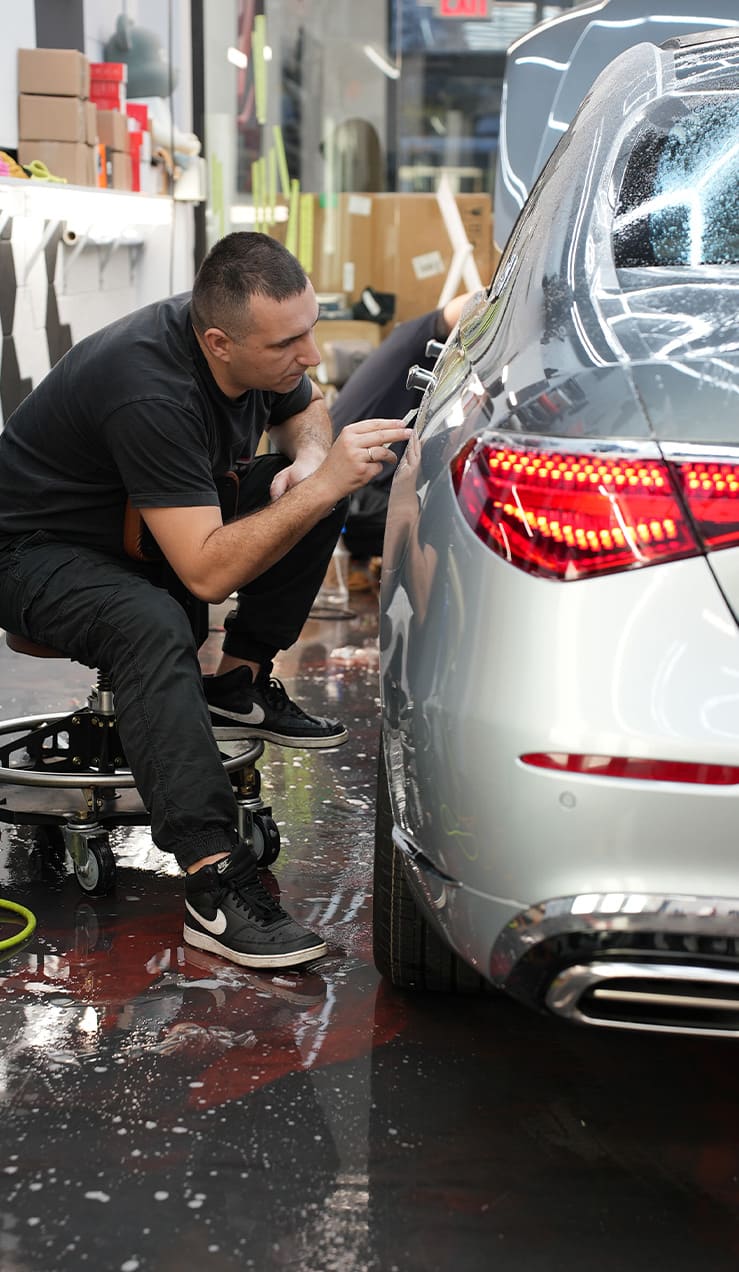 Professional installer applying STEK Paint Protection Film on car hood at Grand Prix Customs Brooklyn NYC
